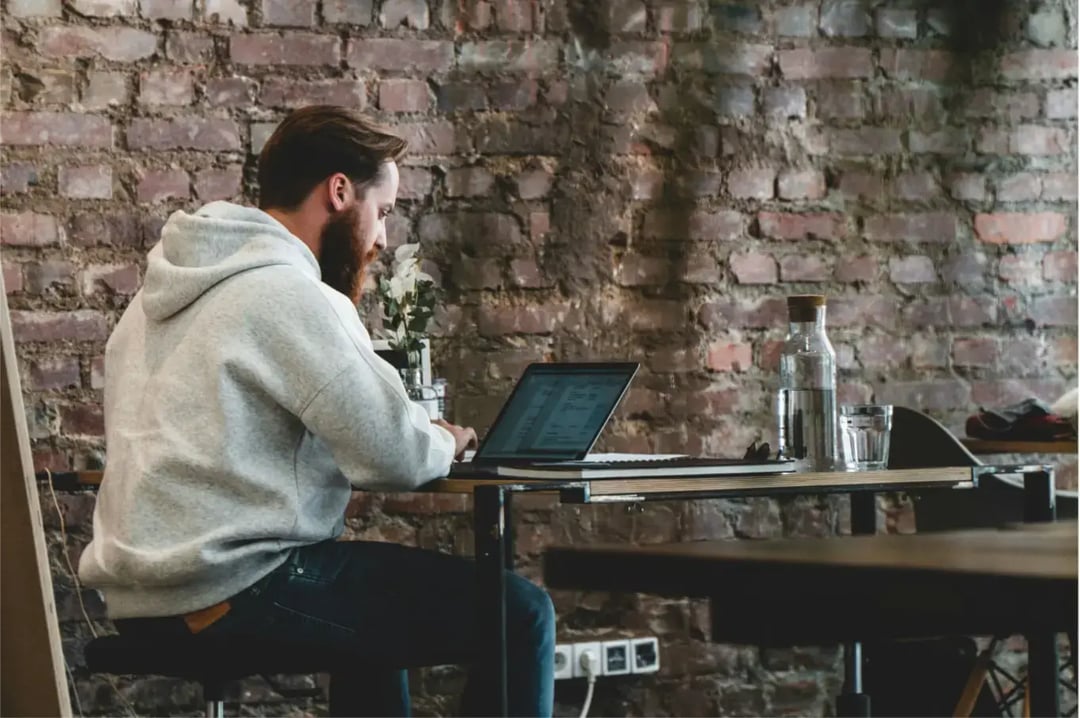 man-in-beige-hoodie-sitting-on-chair-using-laptop-computer