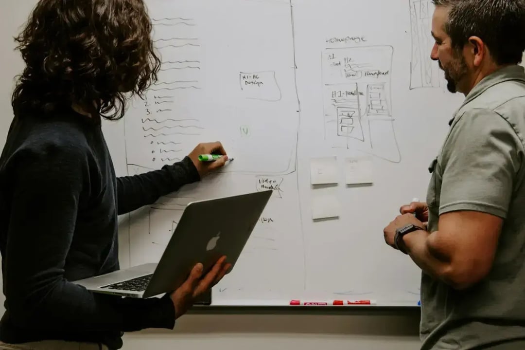 man-wearing-gray-polo-shirt-beside-dry-erase-board