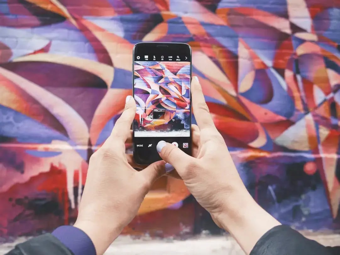 person-taking-photo-of-mural-art-on-smartphone