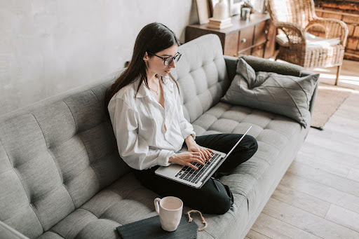 person sitting on a couch using her laptop