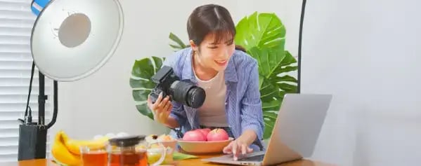 woman-looking-at-laptop-screen-holding-camera