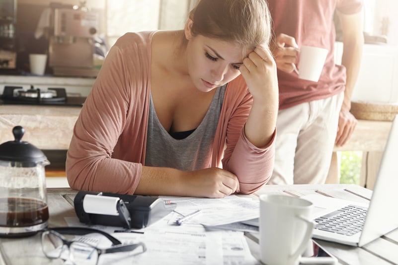 young-casual-female-having-depressed-look-while-managing-family-finances-doing-paperwork-sitting-kitchen-table-with-lots-papers-